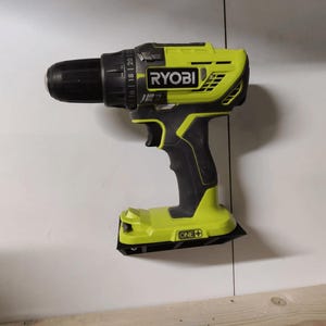 May include: A black and green Ryobi drill with a black handle and a green and black base. The drill has a ONE+ logo on the base.