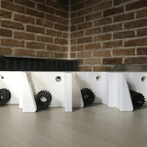 May include: White plastic wall mount with five slots for holding items. Each slot has a black plastic gear-shaped piece.