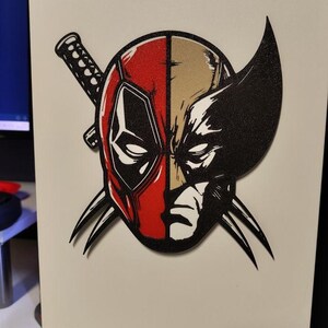 Op de afbeelding: Een witte computerkast met een afbeelding van Deadpool en Wolverine. De Deadpool-kant is rood en zwart, terwijl de Wolverine-kant zwart en bruin is. Gekruiste katana's en klauwen zijn ook aanwezig. De merknaam "NZXT" staat op de kast.