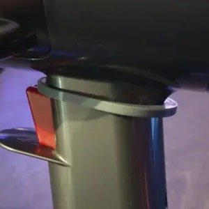 Puede incluir: Primer plano de un secador de pelo negro con un interruptor rojo y una boquilla desmontable gris.