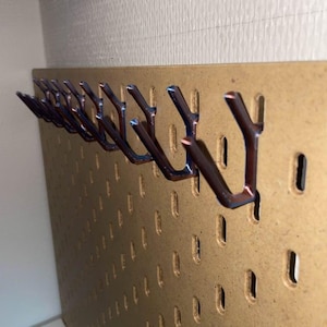 May include: A brown pegboard with multiple metal hooks. The hooks are dark brown with blue accents and are inserted into the pegboard's evenly spaced holes. The pegboard is mounted on a wall.