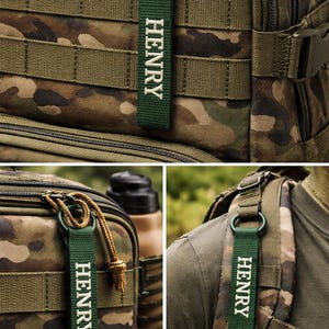 May include: A green fabric tag with the name "HENRY" in white lettering is attached to a camouflage backpack. The tag is looped through a metal ring. The backpack has multiple straps and a zipper.