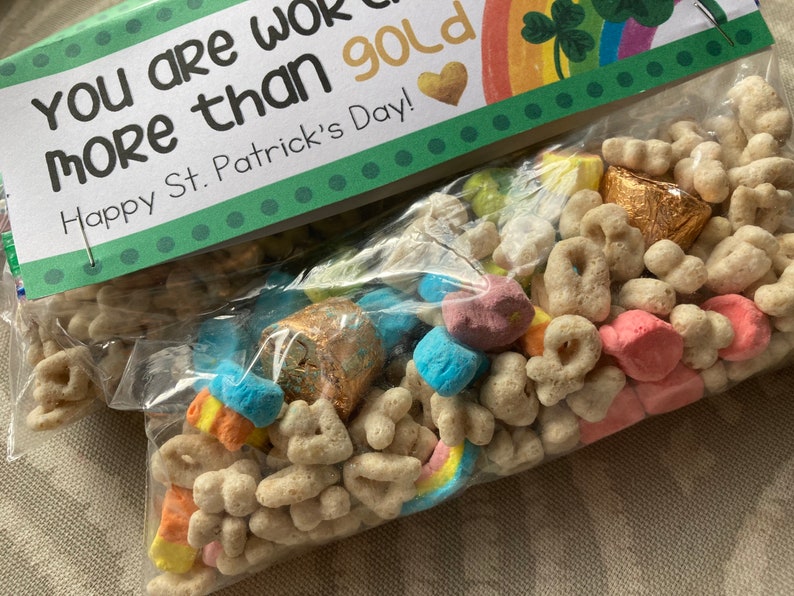 May include: A clear plastic bag filled with a variety of cereal, marshmallows, and chocolate coins. The bag has a green and white tag attached to it that reads "You are worth more than gold Happy St. Patrick's Day!"