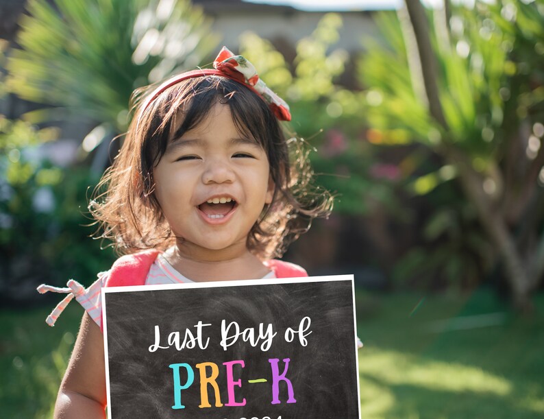 May include: A rectangular chalkboard sign with white text reading Last Day of and colourful text reading PRE-K. The sign is held by a child wearing a striped shirt and a red headband with a floral pattern, set against a bright outdoor background.