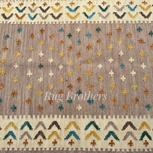 May include: A rectangular rug with a central field of muted gray, adorned with scattered cross-shaped motifs in teal, gold, and white. The border features a repeating geometric pattern in complementary colors. The text "Rug Brothers" is visible.