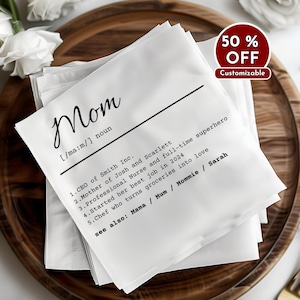 Könnte beinhalten: Weiße Leinen-Serviette mit schwarzem Text, der lautet: "Mom [ma:m/] noun 1. CEO of Smith Inc. 2. Mutter von Josh und Scarlett 3. Professionelle Krankenschwester und Vollzeit-Superheldin 4. Begann ihren besten Job im Jahr 2024 5. Köchin, die Lebensmittel in Liebe verwandelt siehe auch: Mama / Mum / Mommie / Sarah"