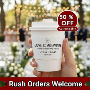 以下が含まれることがあります： 白い紙のコーヒーカップ、蓋とスリーブ付き。「LOVE IS BREWING」と書かれたスリーブには「Emma & Noah」の名前と「02/14/2026」の日付が記載されています。赤い円は50％オフと「カスタマイズ可能」という言葉を示しています。