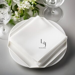 White cloth napkins with "L&J" and "04.24.2026" monogrammed on top.
