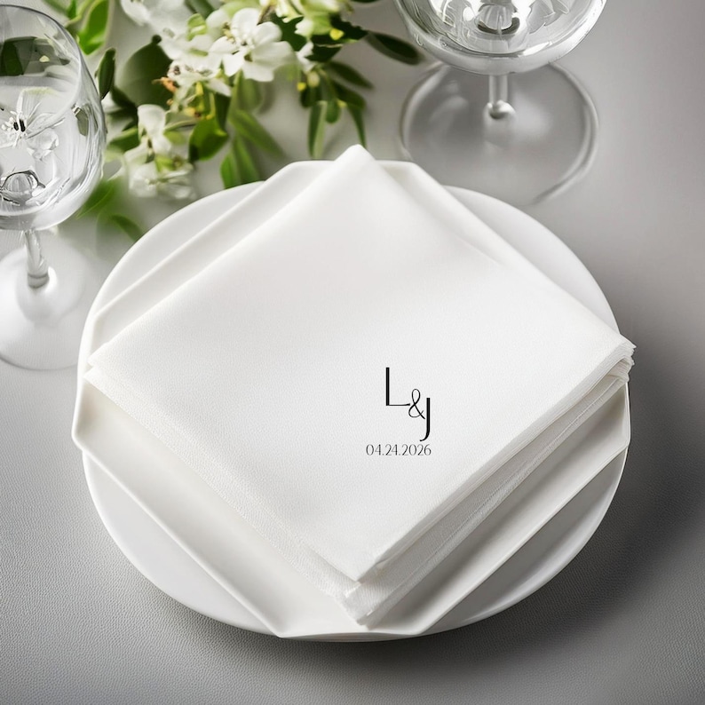 White cloth napkins with "L&J" and "04.24.2026" monogrammed on top.