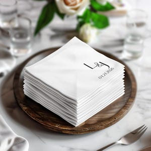 Stack of white linen napkins with monogram "LJ" and date "04.24.2026".