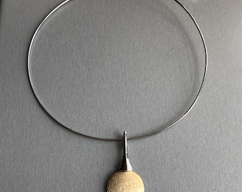Ras de cou rigide avec pendentif de style avant-gardiste. Collier futuriste avec pendentif soleil rond texturé.