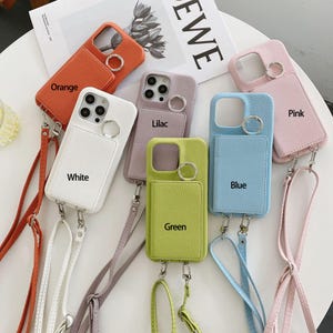 Puede incluir: Seis fundas para teléfono con correas y porta tarjetas de diferentes colores. Los colores son naranja, blanco, lila, verde, azul y rosa. Las fundas tienen un acabado texturizado similar al cuero.