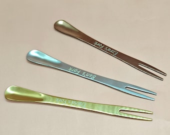 May include: Three metal appetizer forks in bronze, silver, and gold. Each fork has a flat handle with a name engraved on it: "Ezra's Fork", "Ben's Fork", and "David's Fork". The forks have two tines.