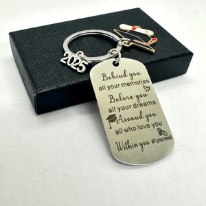 Puede incluir: Un llavero de plata con un dije de gorro de graduación y una etiqueta que dice "Behind you all your memories, Before you all your dreams, Around you all who love you, Within you all you need". La etiqueta también tiene el año 2025 grabado.