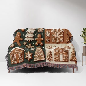 May include: A green and white throw blanket with a gingerbread theme. The blanket features gingerbread houses, gingerbread men, and Christmas trees.