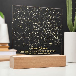 Puede incluir: Una luz nocturna personalizada con un mapa de estrellas, sobre fondo negro y estrellas doradas. El texto dice "Jason Quinn The Night You Were Reborn 02.10.1992 | CLEVELAND, OH".