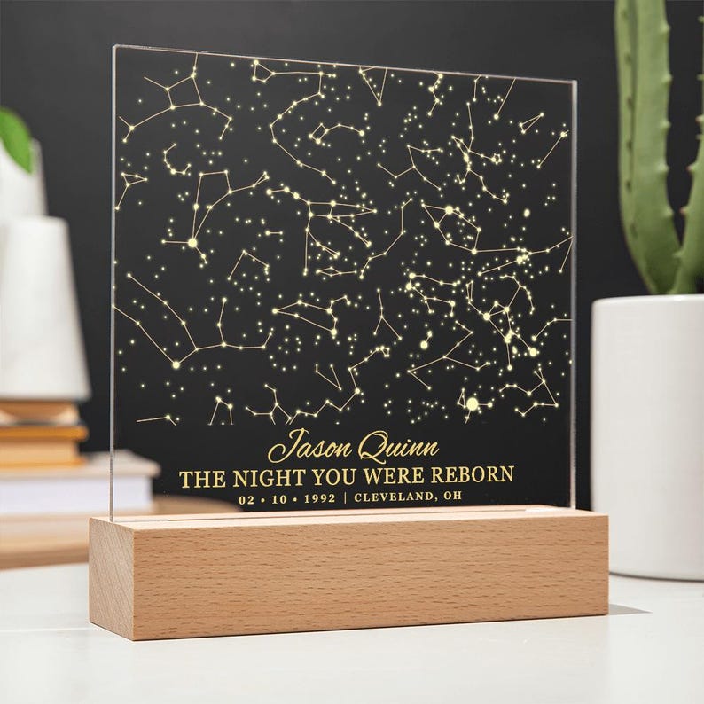 Puede incluir: Una luz nocturna personalizada con un mapa de estrellas, sobre fondo negro y estrellas doradas. El texto dice "Jason Quinn The Night You Were Reborn 02.10.1992 | CLEVELAND, OH".