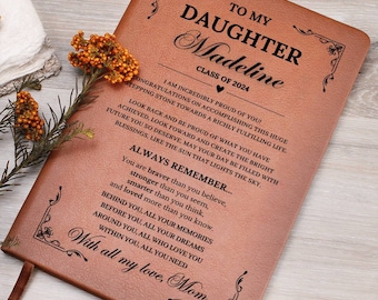 May include: A brown leather journal with a gold embossed design and the text "To My Daughter Madeline Class of 2024" and a message from Mom.