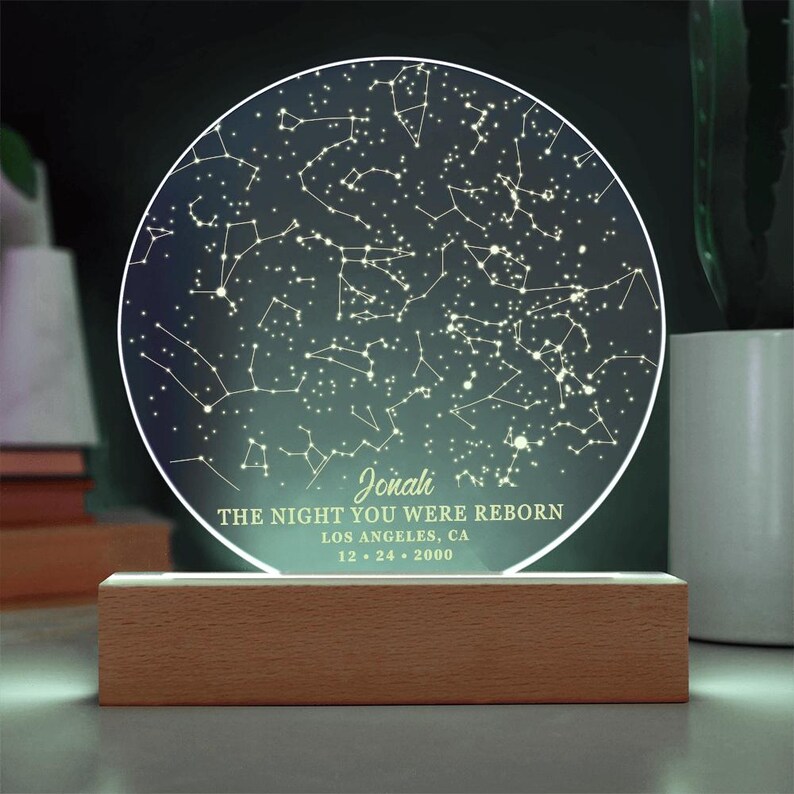 Puede incluir: Un mapa circular del cielo nocturno iluminado con una base de madera. El mapa muestra las constelaciones visibles el 24 de diciembre de 2000 en Los &Aacute;ngeles, California. El texto "Jonah, The Night You Were Reborn" est&aacute; inscrito en el mapa.