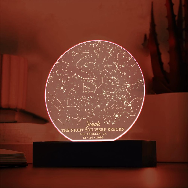 Puede incluir: Un mapa de estrellas redondo, blanco e iluminado con una base negra. El mapa muestra las constelaciones visibles el 24 de diciembre de 2000 en Los &Aacute;ngeles, California. El texto "Jonah, The night you were reborn" est&aacute; impreso debajo del mapa.