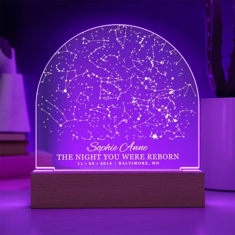 Puede incluir: Una luz nocturna morada con una base de madera. La luz presenta un mapa de constelaciones con el texto "Sophie Anne THE NIGHT YOU WERE REBORN 11.05.2014 | BALTIMORE, MD"