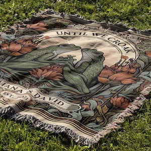 May include: A woven tapestry with a beige background featuring two green frogs, floral designs, and the text "Until We Croak" and "Iana & David Est. 2021".