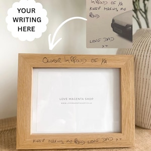 May include: A light oak wood picture frame featuring custom laser-engraved handwriting on the top and bottom borders. The top border reads "OLIVER IM PROUD OF YA" and the bottom border reads "KEEP MAKING ME PROUD LOVE DAD X+". The frame holds a white insert.