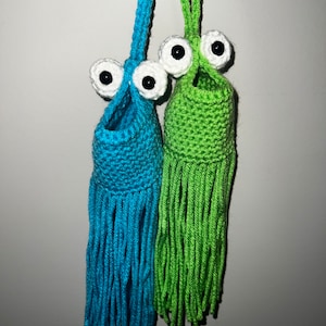 May include: Two crocheted hanging ornaments with large white googly eyes and long fringe. One is blue and the other is green.