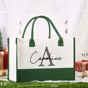 K&ouml;nnte beinhalten: Eine wei&szlig;e und gr&uuml;ne Canvas-Tragetasche mit dem Namen "Caroline" und dem Buchstaben "A" in Grau. Die Tasche ist 43 cm breit, 30 cm hoch und 20 cm tief.