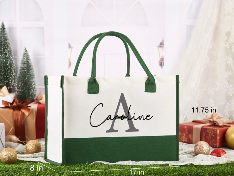 K&ouml;nnte beinhalten: Eine wei&szlig;e und gr&uuml;ne Canvas-Tragetasche mit dem Namen "Caroline" und dem Buchstaben "A" in Grau. Die Tasche ist 43 cm breit, 30 cm hoch und 20 cm tief.