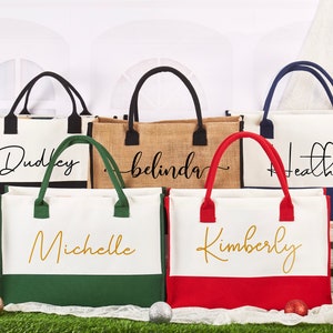 K&ouml;nnte beinhalten: F&uuml;nf personalisierte Tragetaschen mit verschiedenen Namen darauf gedruckt. Die Taschen sind aus Canvas und Jute und haben schwarze, gr&uuml;ne, rote und blaue Akzente. Die Namen auf den Taschen sind Dudley, Belinda, Heather, Michelle und Kimberly.