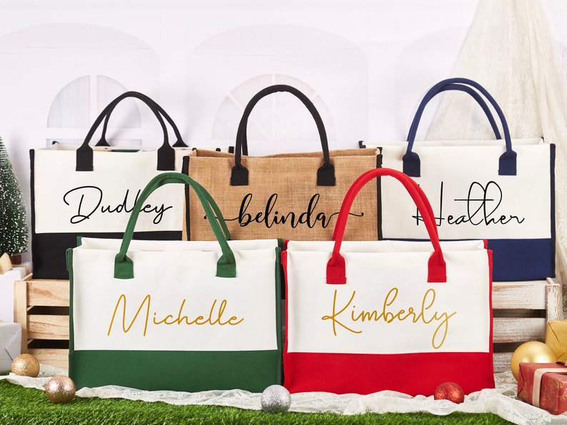 K&ouml;nnte beinhalten: F&uuml;nf personalisierte Tragetaschen mit verschiedenen Namen darauf gedruckt. Die Taschen sind aus Canvas und Jute und haben schwarze, gr&uuml;ne, rote und blaue Akzente. Die Namen auf den Taschen sind Dudley, Belinda, Heather, Michelle und Kimberly.