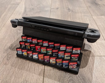 May include: A black Nintendo Switch console with two gray controllers and a stand holding a collection of video game cartridges.