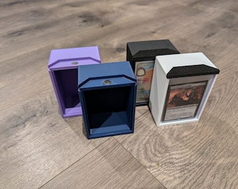 May include: Four different colored card boxes with black lids. The boxes are open and show the inside of the boxes. The boxes are made of plastic and have a smooth finish. The boxes are designed to hold standard-sized trading cards.