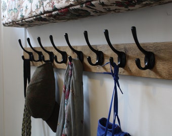 Perchero de madera de estilo antiguo montado en la pared con ganchos de hierro fundido vintage, rústico y hecho a mano.