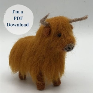 Puede incluir: Una figurita de vaca Highland de fieltro de lana marrón y naranja. La vaca tiene un pelaje largo y peludo y una cara amigable.