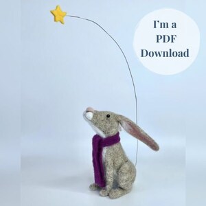 Puede incluir: Un conejo de fieltro con una bufanda morada mira hacia arriba a una estrella amarilla. El texto "I'm a PDF Download" está en un círculo sobre el conejo.
