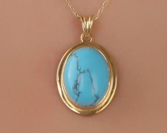 Peut inclure: Un collier doré avec un pendentif ovale bleu clair veiné de bleu foncé. Le pendentif est serti dans un cadre doré et suspendu à une fine chaîne dorée. Le collier est présenté sur un fond neutre. La pierre mesure environ 2 cm de long.