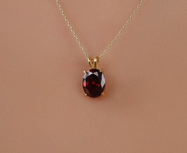 May include: A gold chain necklace with a round red gemstone pendant.