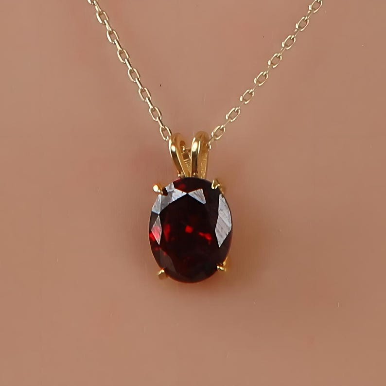 May include: A gold chain necklace with a pendant featuring a large, round, red gemstone.