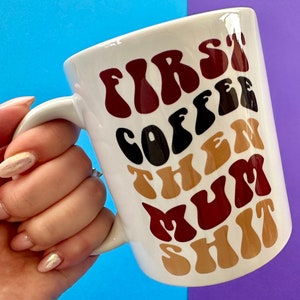May include: White ceramic mug with the text "FIRST COFFEE THEN MUM SHIT" in a retro font. The text is in shades of brown, black, and tan.
