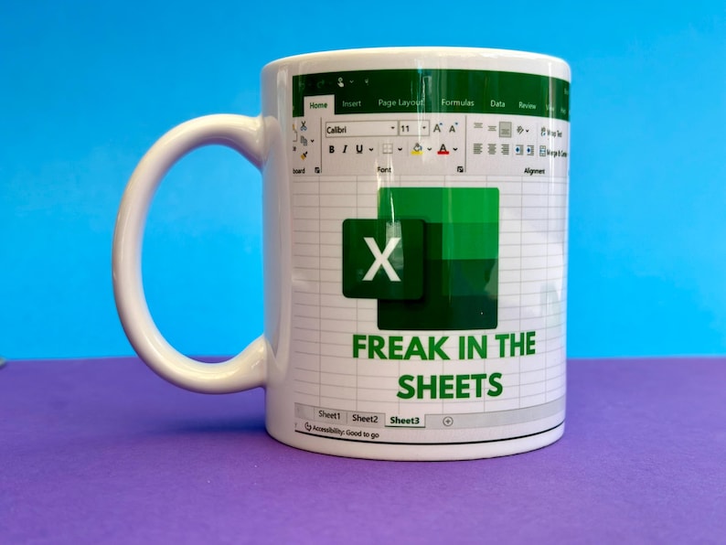 K&ouml;nnte beinhalten: Wei&szlig;e Keramiktasse mit einem Excel-Tabellen-Design und dem Text "FREAK IN THE SHEETS". Die Tasse hat einen wei&szlig;en Henkel und ein gr&uuml;n-wei&szlig;es Design. Die Tasse steht auf einer lila Oberfl&auml;che mit blauem Hintergrund.