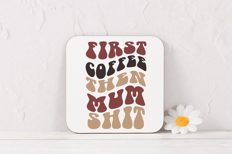 May include: A white coaster with the text "FIRST COFFEE THEN MUM SHIT" in a retro font with brown, red, and black colors.