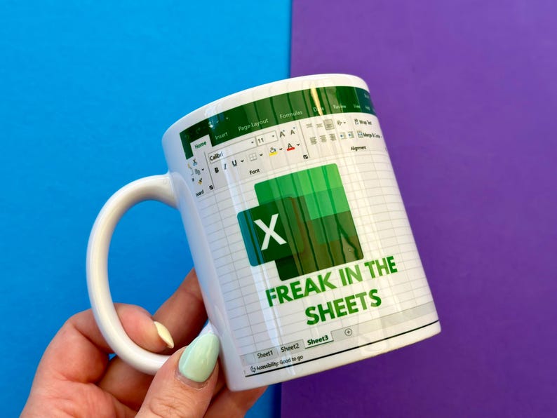 K&ouml;nnte beinhalten: Wei&szlig;e Keramik-Tasse mit einem gr&uuml;n-wei&szlig;en Excel-Tabellen-Design und dem Text "FREAK IN THE SHEETS". Die Tasse hat einen wei&szlig;en Henkel. Der Hintergrund ist blau und lila.