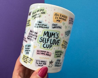 May include: White ceramic mug with the text "Mum's Self Love Cup" and various affirmations in colorful text bubbles. The mug is decorated with hearts, butterflies, and a unicorn illustration.