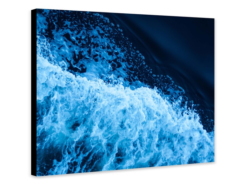 May include: A close-up of a wave crashing in the ocean. The water is a deep blue color and the foam is white. The image is taken from above the wave.