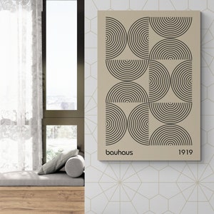 May include: A beige canvas print with a geometric design of black concentric circles arranged in a grid pattern. The print has the text "bauhaus" and "1919" at the bottom.