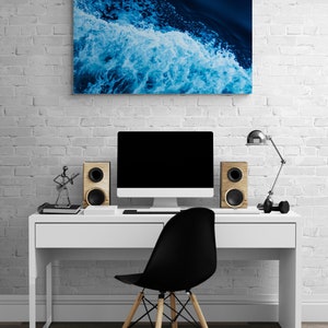 May include: A white desk with a black chair, a computer monitor, and two speakers. A blue and white abstract painting hangs on the wall behind the desk.
