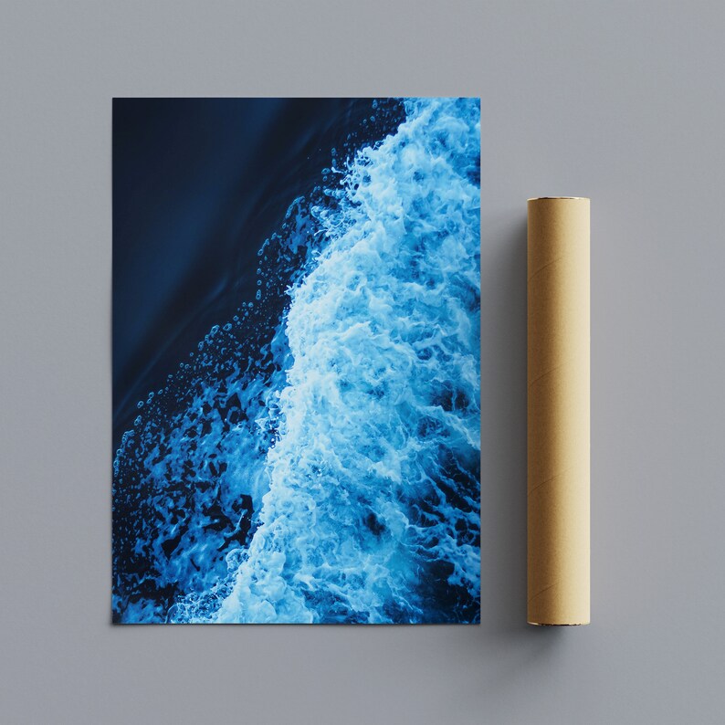 May include: An aerial view of a wave crashing in the ocean. The water is a deep blue color and the foam is white. The background is dark blue.