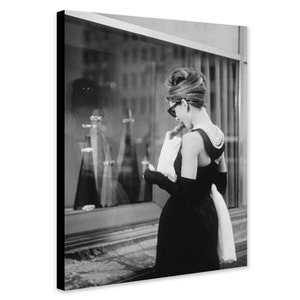 Puede incluir: Una fotografía en blanco y negro de una mujer con un vestido negro y un collar de perlas, mirando un escaparate de joyería.